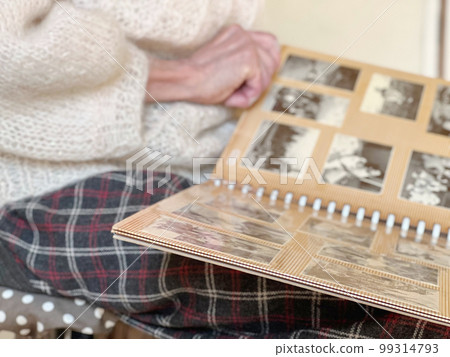 Elderly woman's hand looking at black and white photo album 99314793