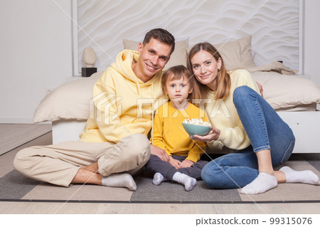 Friendly family, lovely parents in yellow clothes with child son sitting by the bed  99315076