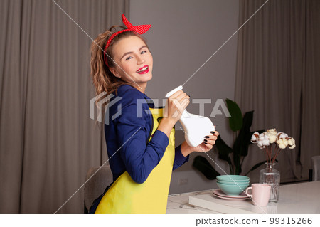 Pretty woman in vintage style. Pin-up woman with trendy makeup. Retro woman cleaning kitchen 99315266