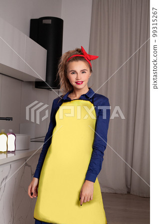 Pretty woman in blue and yellow dress in the kitchen. Pinup housewife with trendy makeup. Pretty woman in blue and yellow dress in the kitchen. Pinup housewife with trendy makeup. 99315267