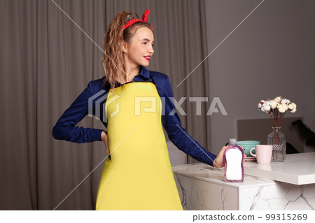 Woman in vintage style showing bottle of detergent. Pin-up woman with trendy makeup. Woman in vintage style showing bottle of detergent. Pin-up woman with trendy makeup. 99315269