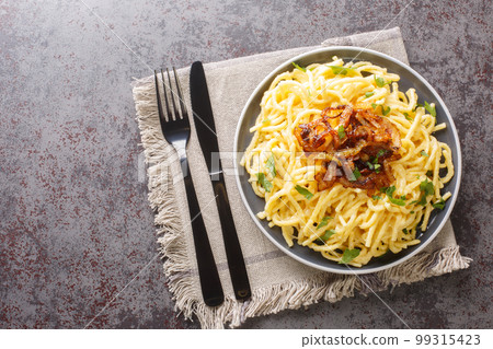 Spatzle egg noodles with melted cheese and fried onions on top close-up in a plate. Horizontal top view Spatzle egg noodles with melted cheese and fried onions on top close-up in a plate. Horizontal top view 99315423