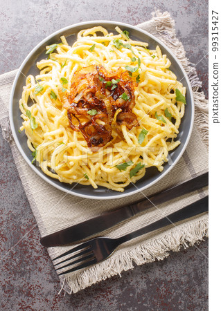 Tyrolean Cheese Noodles or Pasta called Kaesespaetzle with Fried Onion closeup on the plate. Vertical top view 99315427