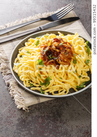 Tyrolean Cheese Noodles or Pasta called Kaesespaetzle with Fried Onion closeup on the plate. Vertical 99315432