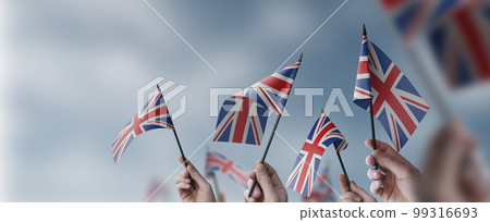 A group of people holding small flags of the United Kingdom in their hands A group of people holding small flags of the United Kingdom in their hands 99316693