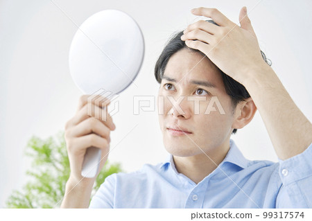 Man worried about looking at his hair in the mirror Man worried about looking at his hair in the mirror 99317574