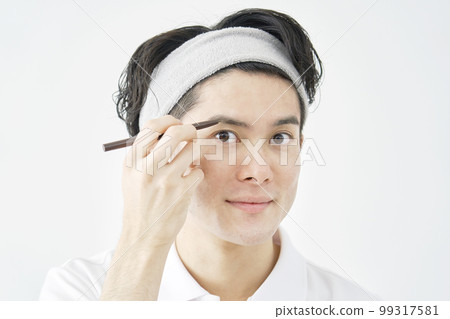 一個男人用眉筆劃眉毛 白色背景 99317581