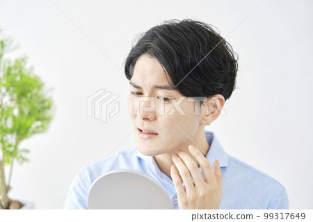 A man suffering from rough skin looking in the mirror 99317649