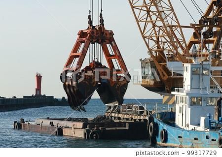 Scooping sand in harbor by dredger 99317729