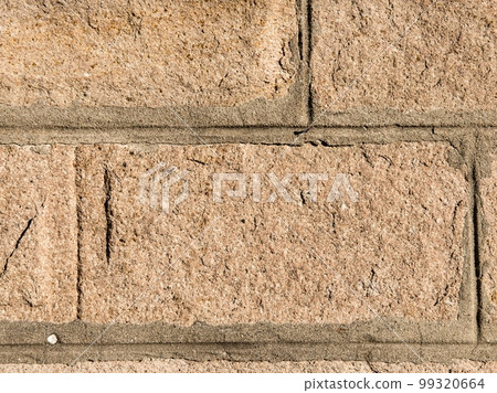 texture of the stone. A yellow stone decorated in the form of a brick in bright sunlight. 99320664