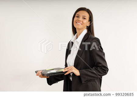 Portrait of happy smiling young woman with laptop in her hands, dressed in white shirt and black jacket on isolated white background. Studio shot of brunette girl with laptop computer. 99320685