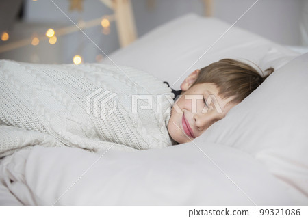 The little boy sleeps and smiles in his sleep, he has a good dream. The little boy sleeps and smiles in his sleep, he has a good dream. 99321086