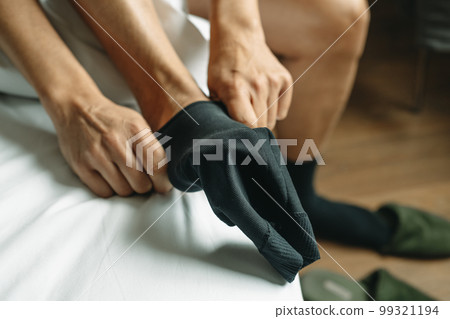 man putting on a compression sock sitting on the bed man putting on a compression sock sitting on the bed 99321194