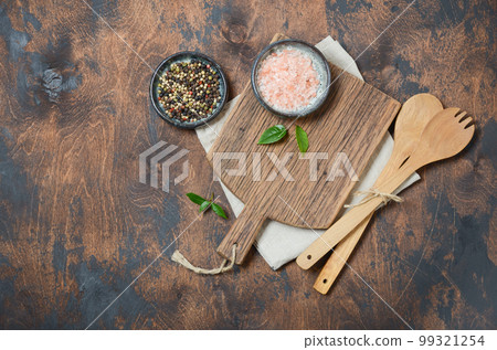 Wooden kitchen utensils and spices. Wooden spoons, cutting board, napkin and spices on a old wooden table. Top view, copy space. 99321254