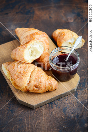 Freshly baked croissants with jam on dark wooden background. Freshly baked croissants with jam on dark wooden background. 99321306