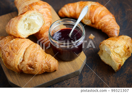 Freshly baked croissants with jam on dark wooden background. Freshly baked croissants with jam on dark wooden background. 99321307