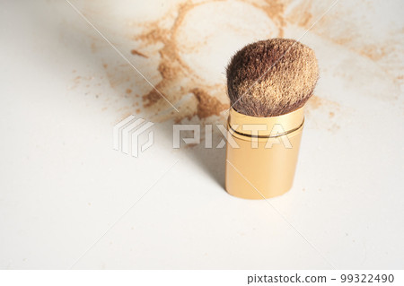 Soft cosmetic brush, with shining sparkling powder on the bristles.The powder is scattered on the table, on a light background with space to copy in the concept of beauty and makeup.High quality photo 99322490
