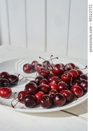 Close-up of a plate of ripe cherries in a white plate on a white wooden background. With space to copy. High quality photo 99322551