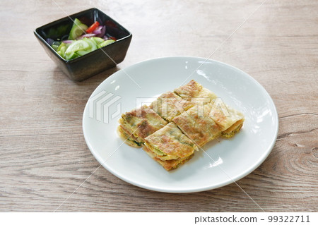 fried Murtabak roti stuffed beef meat on plate dipping sweet pickled cucumber sauce fried Murtabak roti stuffed beef meat on plate dipping sweet pickled cucumber sauce 99322711