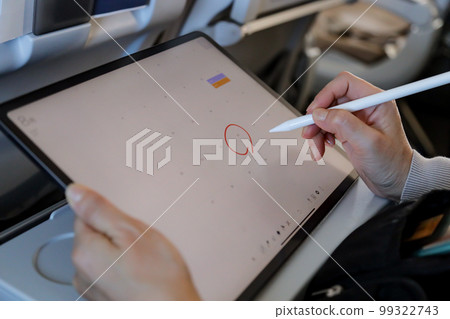 在飛機上操作平板電腦並將其寫入日曆的人 在飛機上操作平板電腦並將其寫入日曆的人 99322743