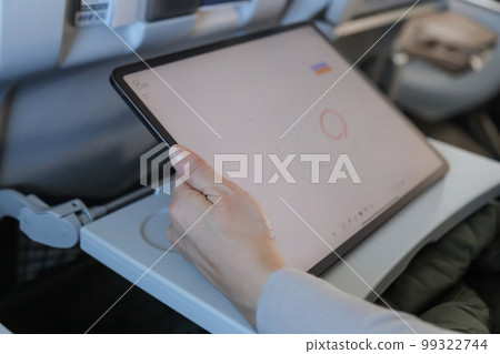 在飛機上操作平板電腦並將其寫入日曆的人 在飛機上操作平板電腦並將其寫入日曆的人 99322744