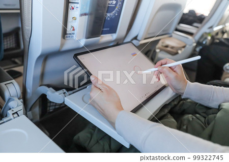 在飛機上操作平板電腦並將其寫入日曆的人 99322745