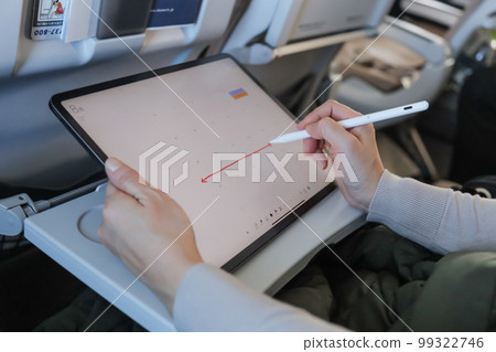 在飛機上操作平板電腦並將其寫入日曆的人 在飛機上操作平板電腦並將其寫入日曆的人 99322746