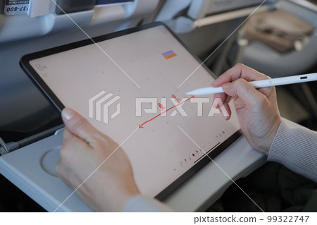 在飛機上操作平板電腦並將其寫入日曆的人 在飛機上操作平板電腦並將其寫入日曆的人 99322747