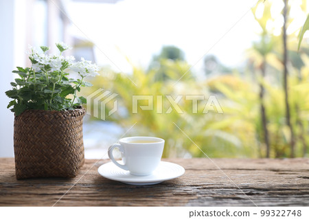 White tea cup and Verbena plant pot wooden table balcony White tea cup and Verbena plant pot wooden table balcony 99322748
