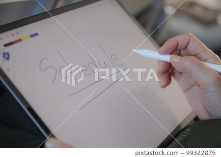 A person operating a tablet on an airplane, writing letters on a memo app 99322876