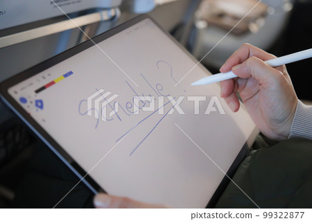 A person operating a tablet on an airplane, writing letters on a memo app 99322877