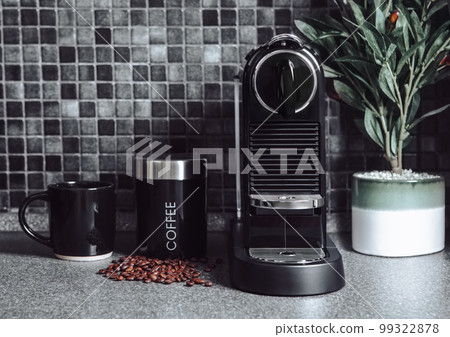 Black kitchen with home coffee machine and beans with cup and olive plant. Black kitchen with home coffee machine and beans with cup and olive plant. 99322878
