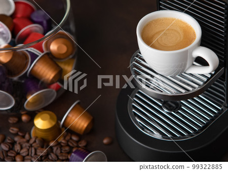 Coffee machine pods capsules with cup and raw aroma coffee beans on brown. Coffee machine pods capsules with cup and raw aroma coffee beans on brown. 99322885