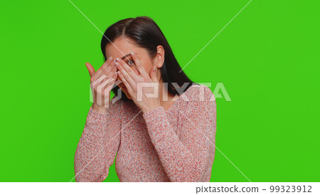 Nosy curious young woman closing eyes with hand and spying through fingers, hiding and peeping Nosy curious young woman closing eyes with hand and spying through fingers, hiding and peeping 99323912