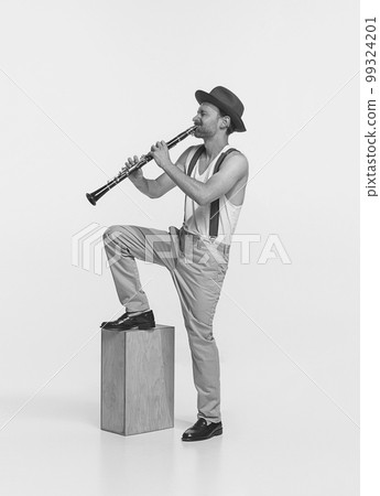 Portrait of young man playing clarinet isolated over white studio background. Expressive performance. Black and white photography 99324201