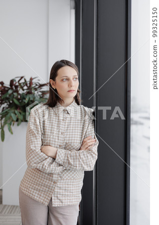 confident business woman stands at window in office looking into distance. thoughtful female confident business woman stands at window in office looking into distance. thoughtful female 99325150