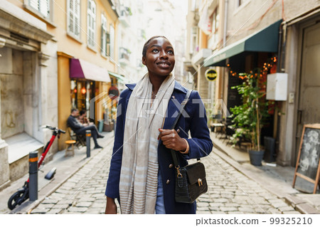 Young african woman walks alone on europe street Young african woman walks alone on europe street 99325210