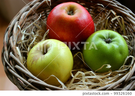 Yellow, Red And Green Apple Fruits In Wood Swarf In A Wicker Pot Closeup Stock Photo 99326160