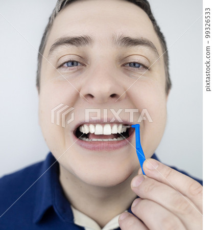 Interdental brush. A man shows a brush for cleaning the interdental space. Brush for cleaning teeth and daily oral care. Dentistry and orthodontics  99326533