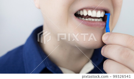 Interdental brush. A man shows a brush for cleaning the interdental space. Brush for cleaning teeth and daily oral care. Dentistry and orthodontics Interdental brush. A man shows a brush for cleaning the interdental space. Brush for cleaning teeth and daily oral care. Dentistry and orthodontics 99326541