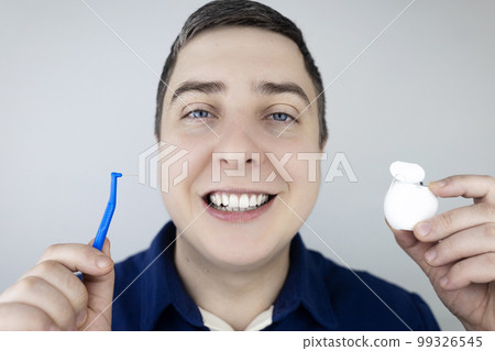 Interdental brush. A man shows a brush for cleaning the interdental space. Brush for cleaning teeth and daily oral care. Dentistry and orthodontics  99326545
