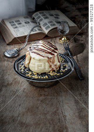 Cinnamon roll topped with rich cream cheese frosting served with Metal fork on old rustic wooden background. Cinnamon roll topped with rich cream cheese frosting served with Metal fork on old rustic wooden background. 99327128