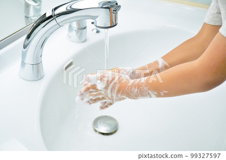 An infant washing his hands with running water after washing his hands daily with foamed soap up to his arms 99327597