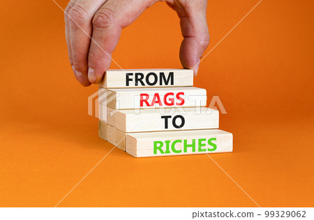 Rags or riches symbol. Concept words From rags to riches on wooden blocks. Beautiful orange table orange background. Businessman hand. Business rags or riches concept. Copy space. Rags or riches symbol. Concept words From rags to riches on wooden blocks. Beautiful orange table orange background. Businessman hand. Business rags or riches concept. Copy space. 99329062