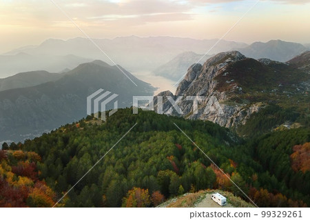 Drone view of parked big modern camper motorhome on background of mountains and Boka Kotorska bay, Montenegro. Family vacation travel RV. Bicycles attached to caravan. Travel and adventure. 99329261