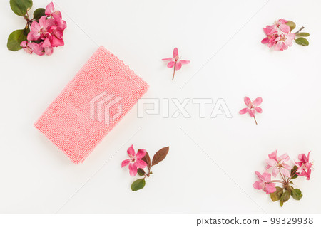New folded microfiber cloth for cleaning on white with spring flowers background. Cleaning micro fabric for dusting and polishing. Domestic household cleaning service concept. Top view 99329938