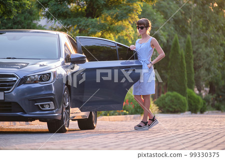 Young woman standing beside her car waiting for someone. Travelling and vacations concept. Young woman standing beside her car waiting for someone. Travelling and vacations concept. 99330375