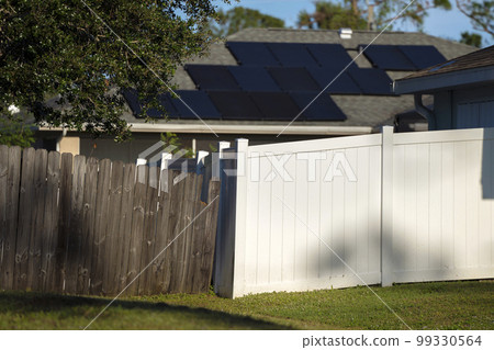 White vinyl picket fence on green lawn surrounding property grounds for backyard protection and privacy White vinyl picket fence on green lawn surrounding property grounds for backyard protection and privacy 99330564