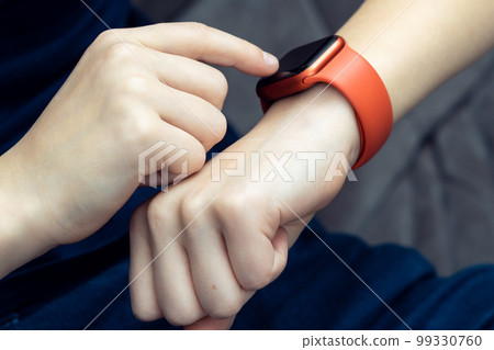 Unrecognizable teenager male hand typing on red smart watch on hand, wrist watch technology. Call and health application 99330760