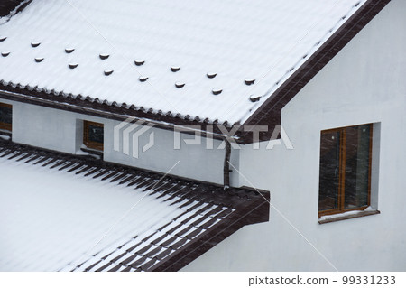 Snow guard for safety in winter on house roof top covered with steel shingles. Tiled covering of building Snow guard for safety in winter on house roof top covered with steel shingles. Tiled covering of building 99331233